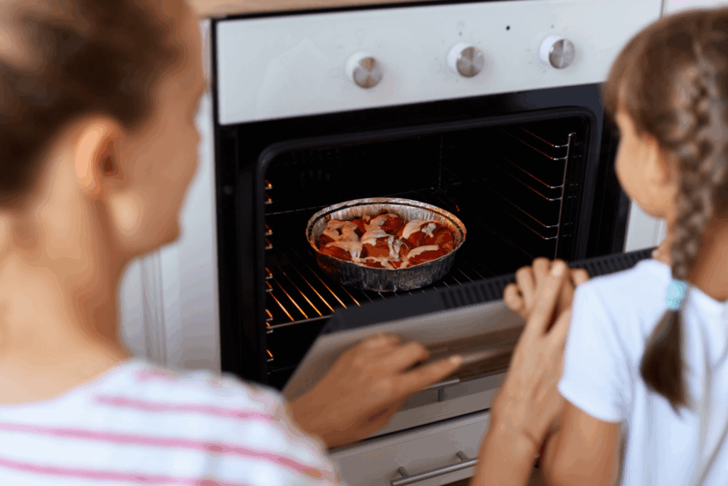 Mulher e criança colocando comida em um forno de embutir da Casas Bahia