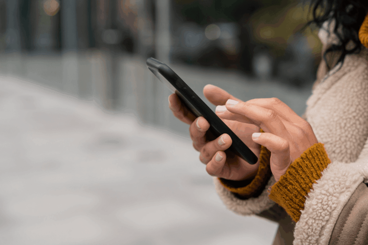 Mulher na rua mexendo em um iPhone 15 Pro Max da Casas Bahia
