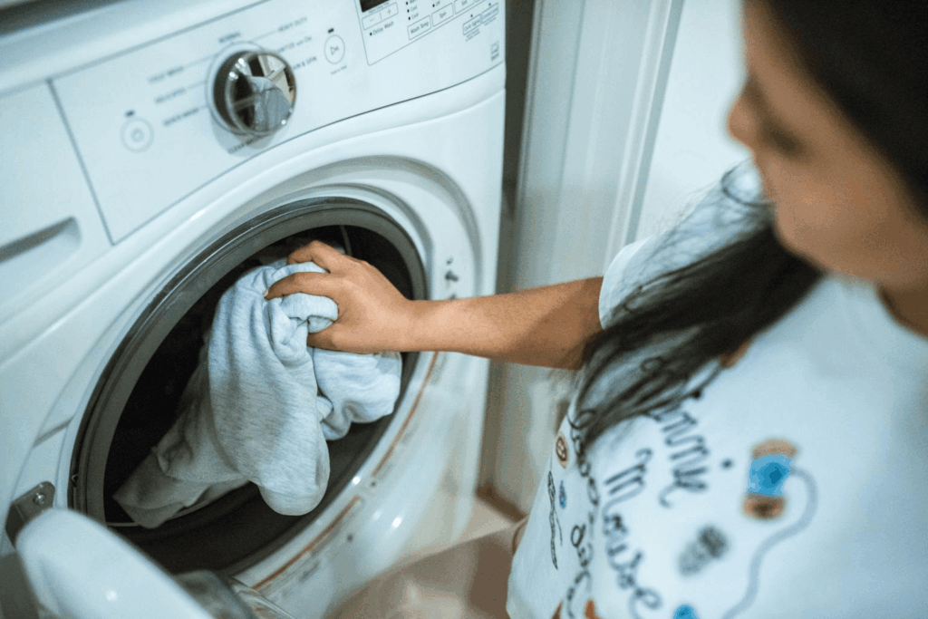 Mulher colocando roupa na lava e seca da Casas Bahia