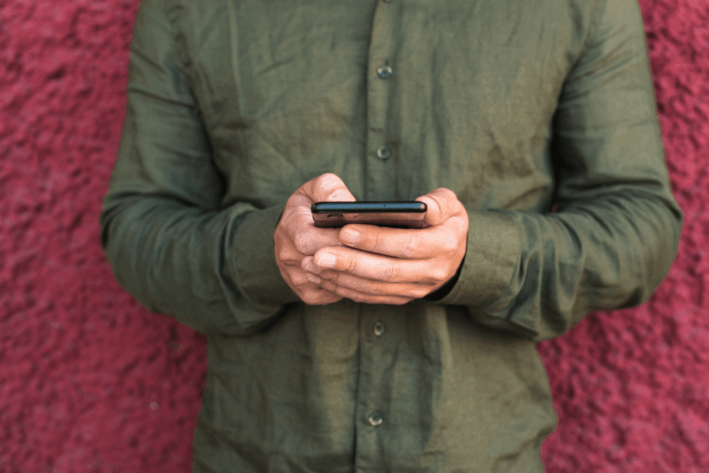 Homem de camisa verde mexendo em um iPhone 16 da Casas Bahia