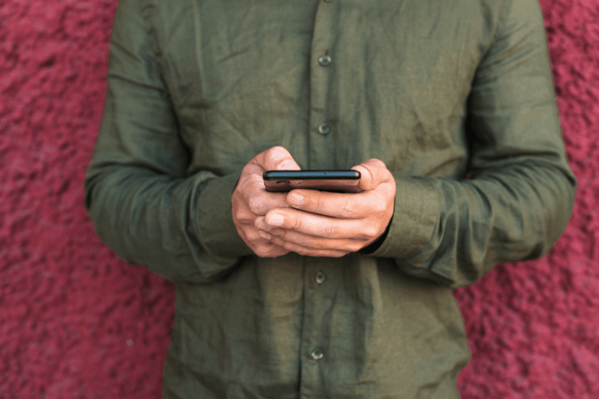 Homem de camisa verde mexendo em um iPhone 16 da Casas Bahia
