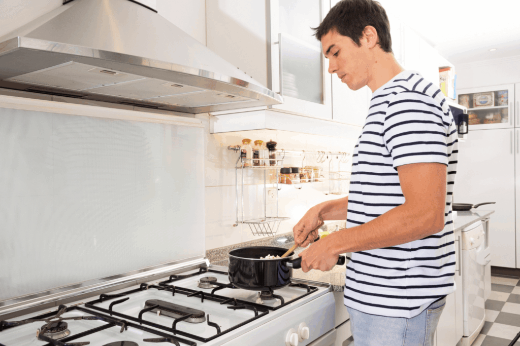 homem cozinhando com auxílio de uma coifa da Casas Bahia
